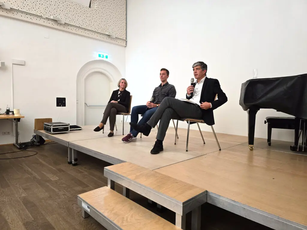 Ausschnitt des Kamingesprächs - drei Personen auf einer Bühne.