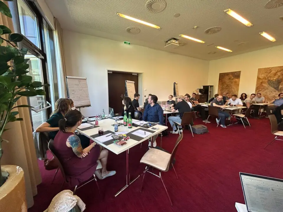 Menschen in einem Raum mit Tischen und Stühlen