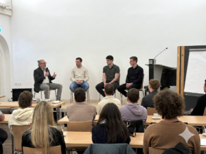 Inno.TALENT_KI-Modul2l Vier Personen sitzen auf einer Bühne vor Gästen.